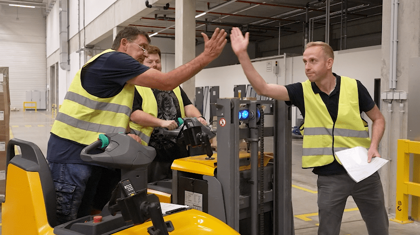 Teamwork in Fabrikhalle Logistikteam gibt sich High-Five